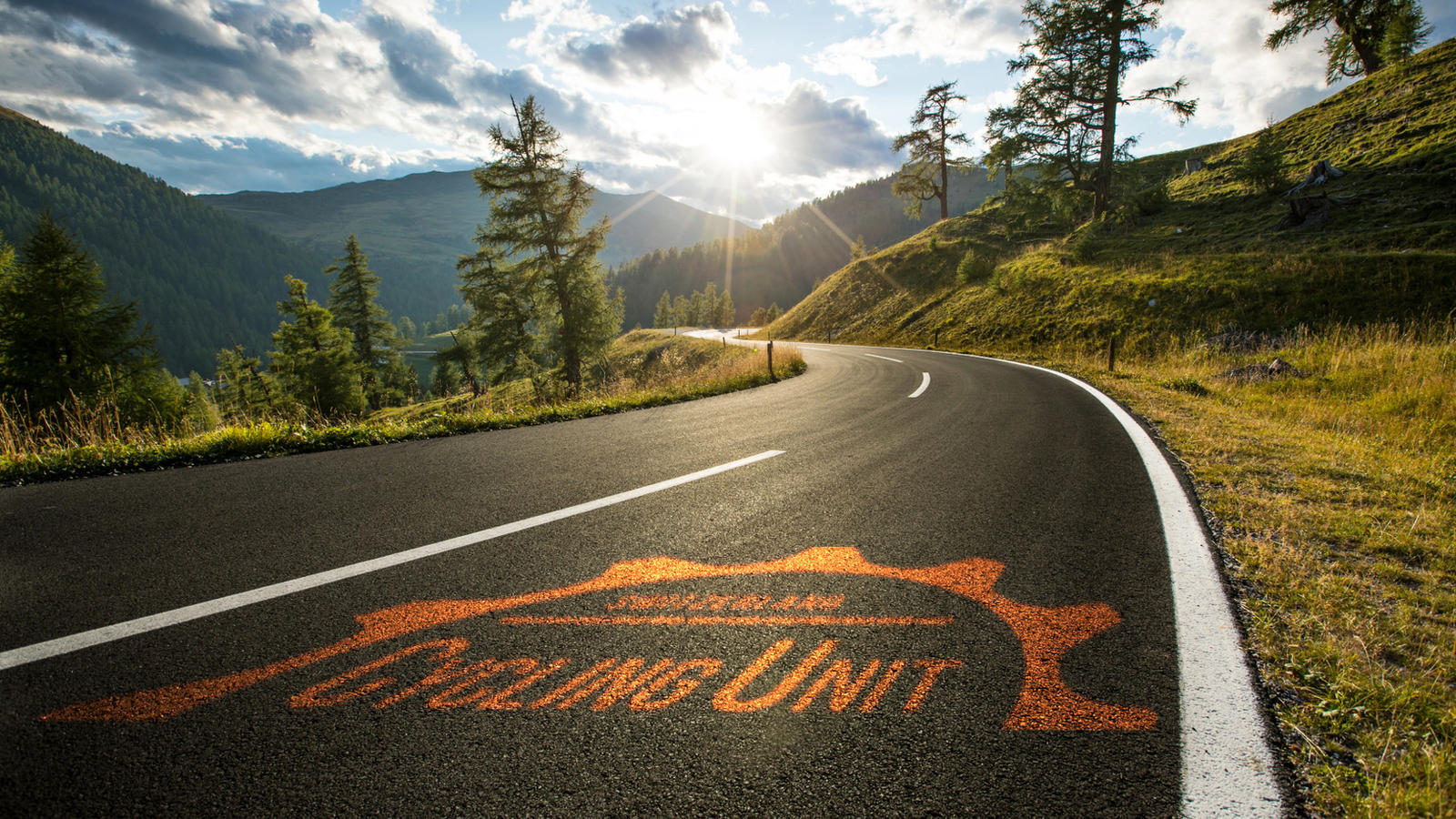 Cycling-Unit-Logo auf eine Passstrasse gemalt, Abendstimmung in den Bergen