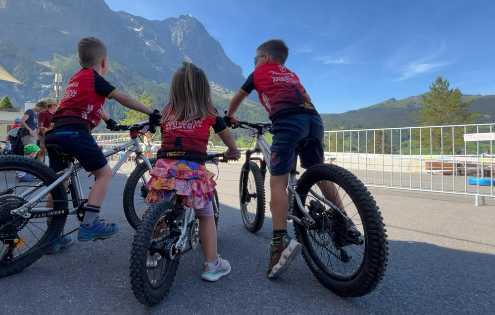 Drei Kinder auf Mountainbikes im Swiss Bike Park vor Bergpanorama